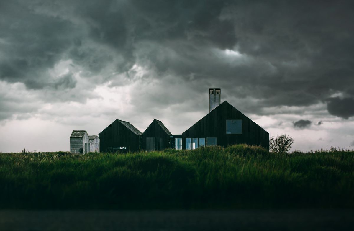 Dark gabled house under a heavy storm sky