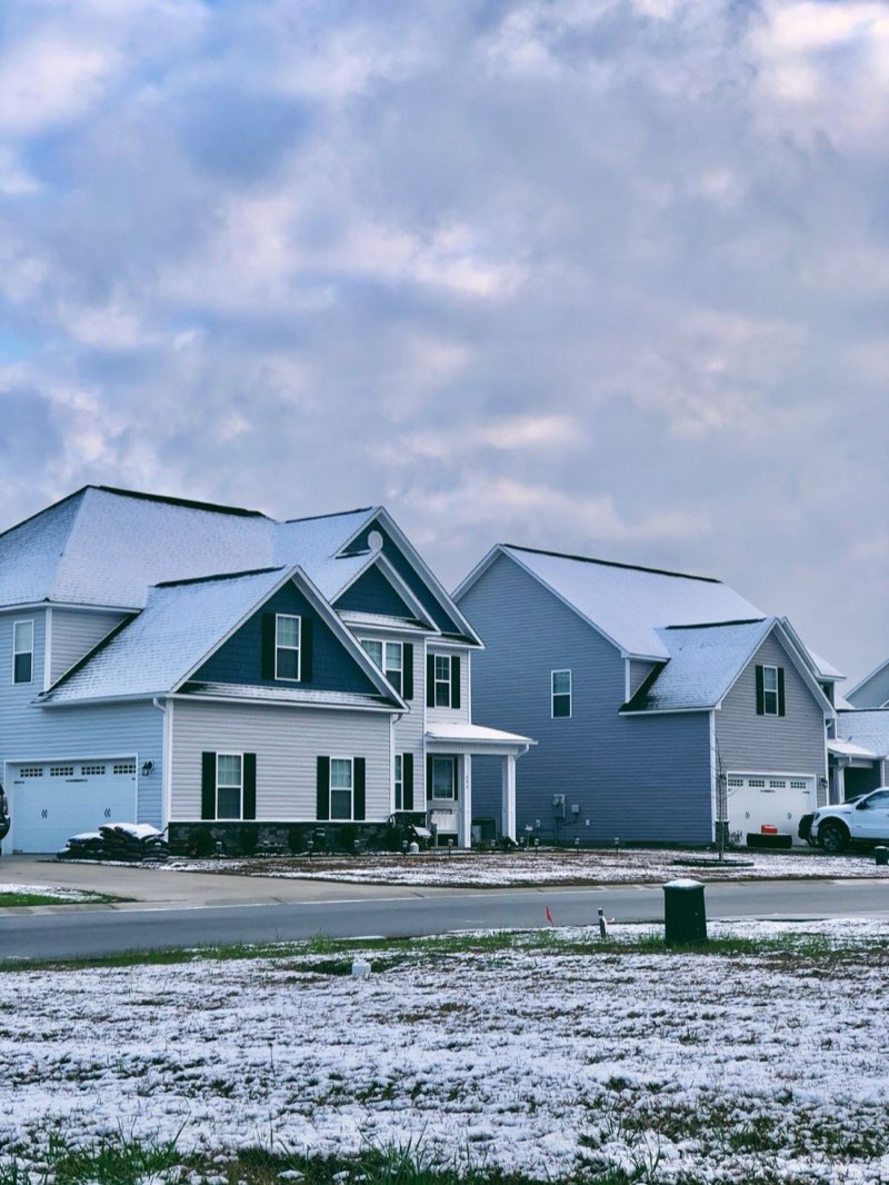 Snow-dusted rooflines on a residential street under a winter sky